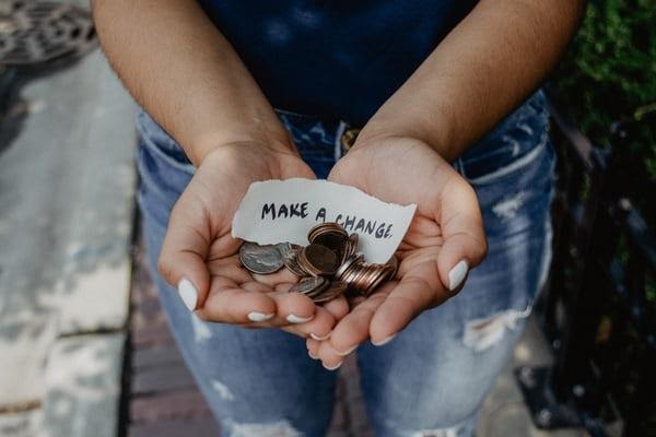Hand with coins with a note saying "make a change".