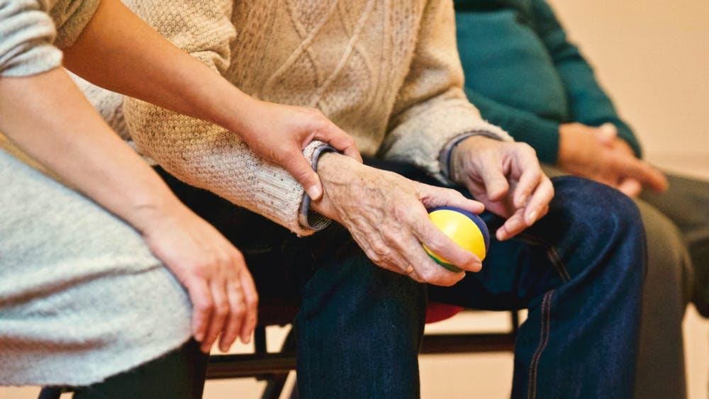 Woman with hand resting on the hand of an old gentleman.