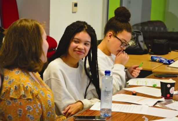 Group of girls sat at a desk talking