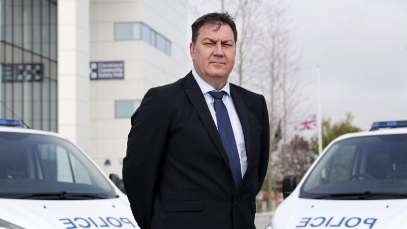 PCC Steve Turner stood in front of two police vans