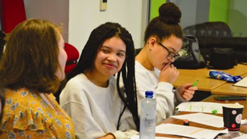 Group of girls sat at a desk talking