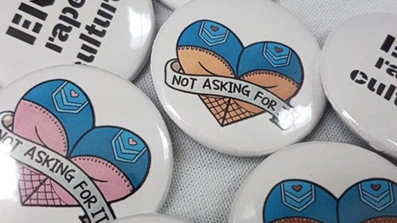 A collection of pin badges with slogans such as "consent is hot, rape is not"